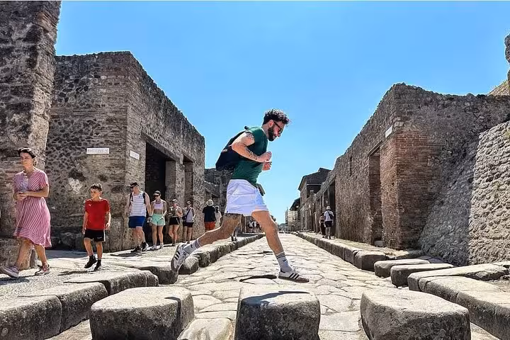 Tourists explore ancient streets of Pompeii on a sunny day, highlighting vibrant day trips from Sorrento.