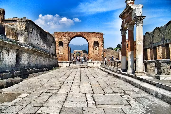 Stroll through the historic streets of Pompeii with iconic arches and columns, part of our immersive Vesuvius tour.