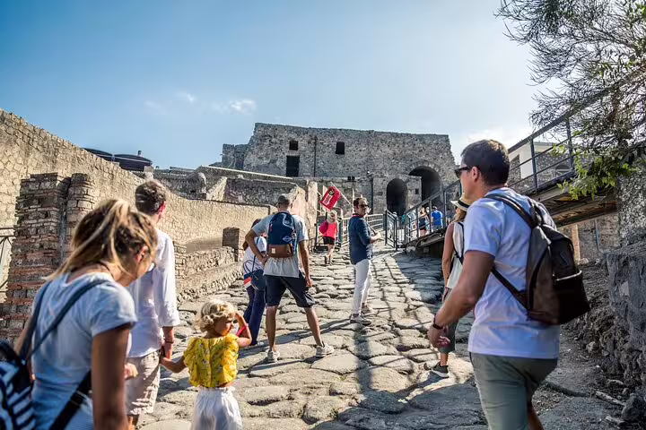 Tourists exploring ancient ruins on a guided Pompeii tour, highlighting the historic architecture and vibrant atmosphere.