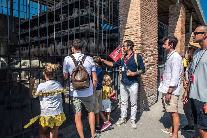 Tour group exploring artifacts at Pompeii ruins with guide from Naples day trip.