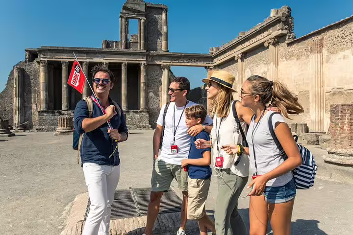 Tour guide showing a family the ancient ruins of Pompeii on a sunny day during a guided tour from Sorrento.