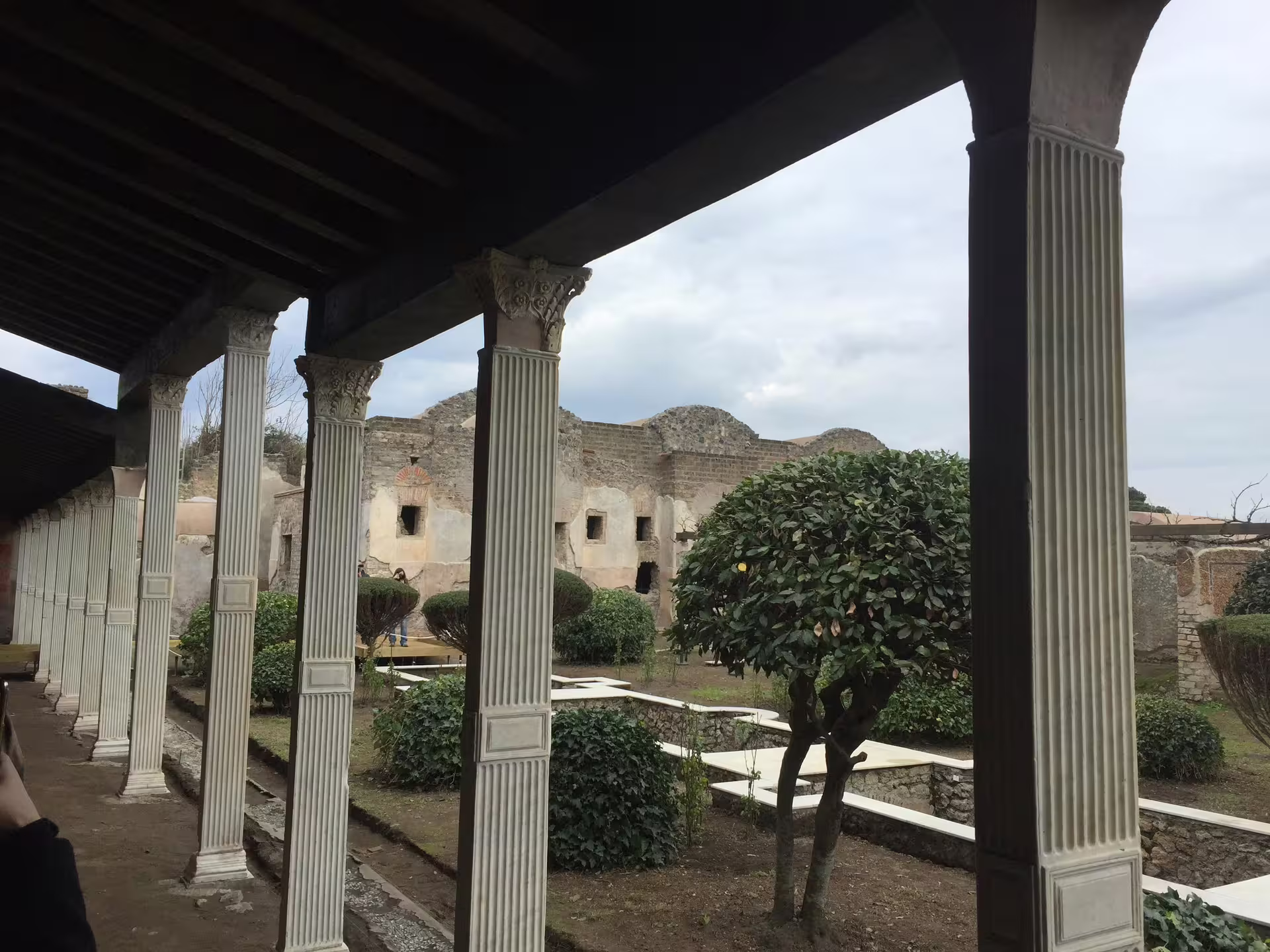 Pompeii peristyle garden with fluted columns and ancient villa ruins on a half day group tour from Naples
