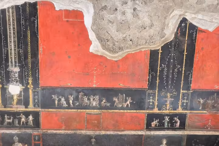 Discover intricate red and black frescoes of Pompeii's ruins, highlighting Roman artistry on the Amalfi Coast tour.