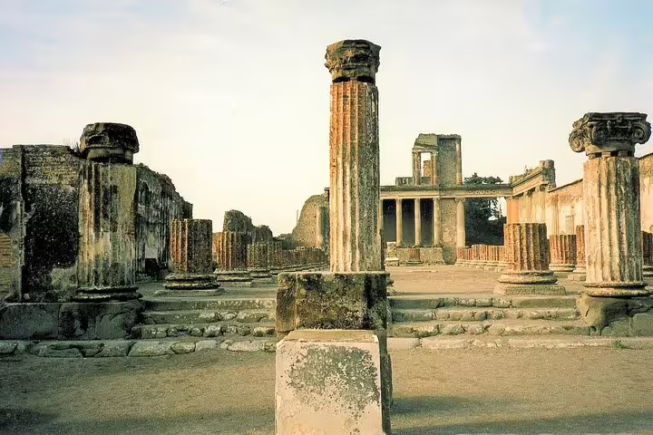 Pompeii ruins with ancient columns and forum walkway, half day group tour from Naples with guide