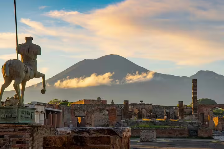 Ancient ruins of Pompeii with bronze centaur statue and Mount Vesuvius at sunset