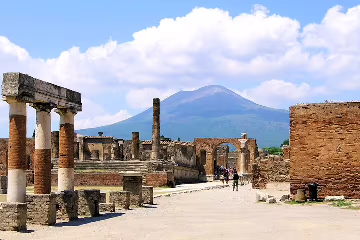 Ancient Roman ruins of Pompeii with stone columns and Mount Vesuvius in the background