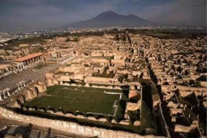 Aerial view of ancient Pompeii ruins with Mount Vesuvius in the background on a full-day guided tour from Naples