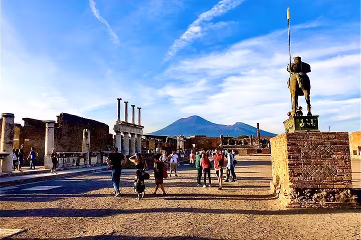 Visitors walking through the ruins of Pompeii with Mount Vesuvius in the background, showcasing a breathtaking view.
