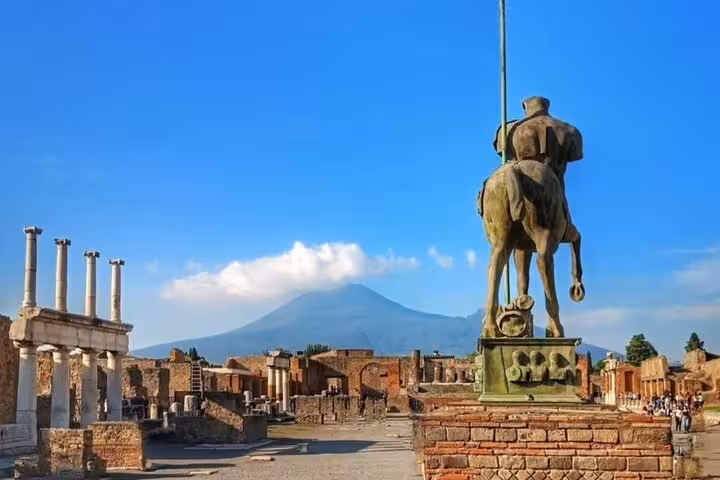 Statue overlooking Pompeii ruins with majestic Mount Vesuvius in the background on a Sorrento day trip tour.