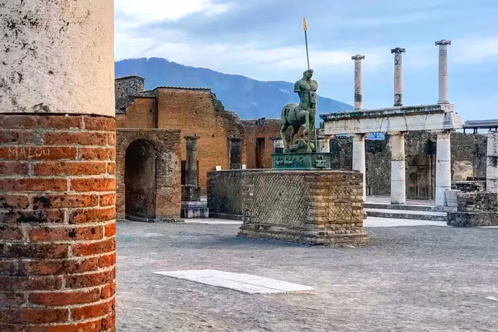 Statue and ruins in Pompeii with Mt. Vesuvius in the background, featured in the Semi-Private Tour from Positano.