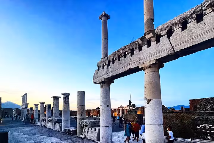 Explore ancient Pompeii ruins at sunset, showcasing towering columns and vibrant evening sky on a guided tour.