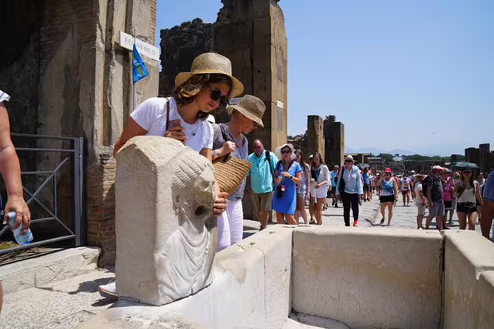 Tourists exploring ancient ruins at Pompeii, Italy, marveling at historical artifacts on a sunny day tour.