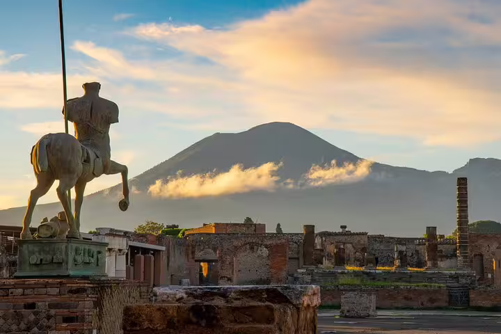 Centaur statue overlooking ancient Pompeii ruins with Mount Vesuvius at sunset