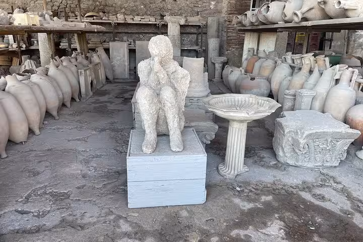 Ancient Pompeii ruins with plaster cast figure and pottery, featured in Vesuvius and wine tasting tour from Amalfi Coast.