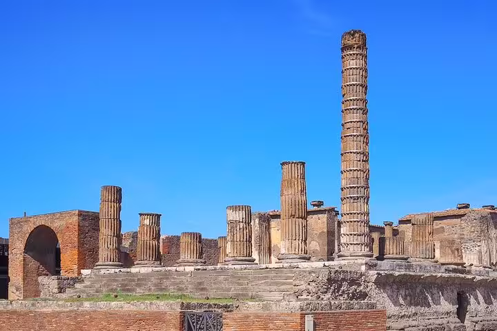 Ancient Roman columns and ruins of the Temple of Jupiter in Pompeii under a clear blue sky