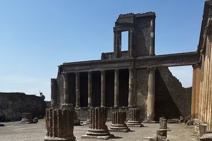 Ruins of a grand temple in Pompeii with remaining columns, showcasing ancient architecture on a guided tour from Sorrento.