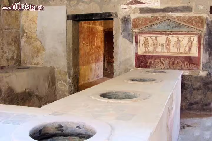 Ancient thermopolium in Pompeii with frescoed walls and stone counters visited on a private Positano Pompeii Vesuvius tour