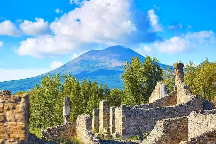 Explore the ancient ruins of Pompeii with Mount Vesuvius in the background on the Amalfi tour, offering a rich historical experience.