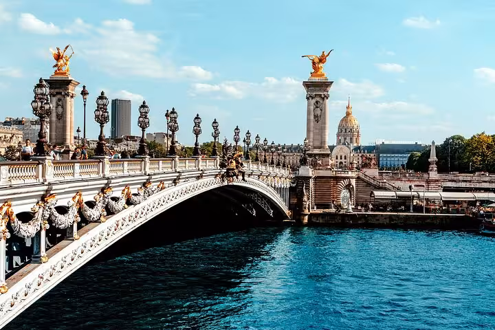 Ornate Pont Alexandre III bridge over the Seine River with gilded statues and Les Invalides dome in Paris