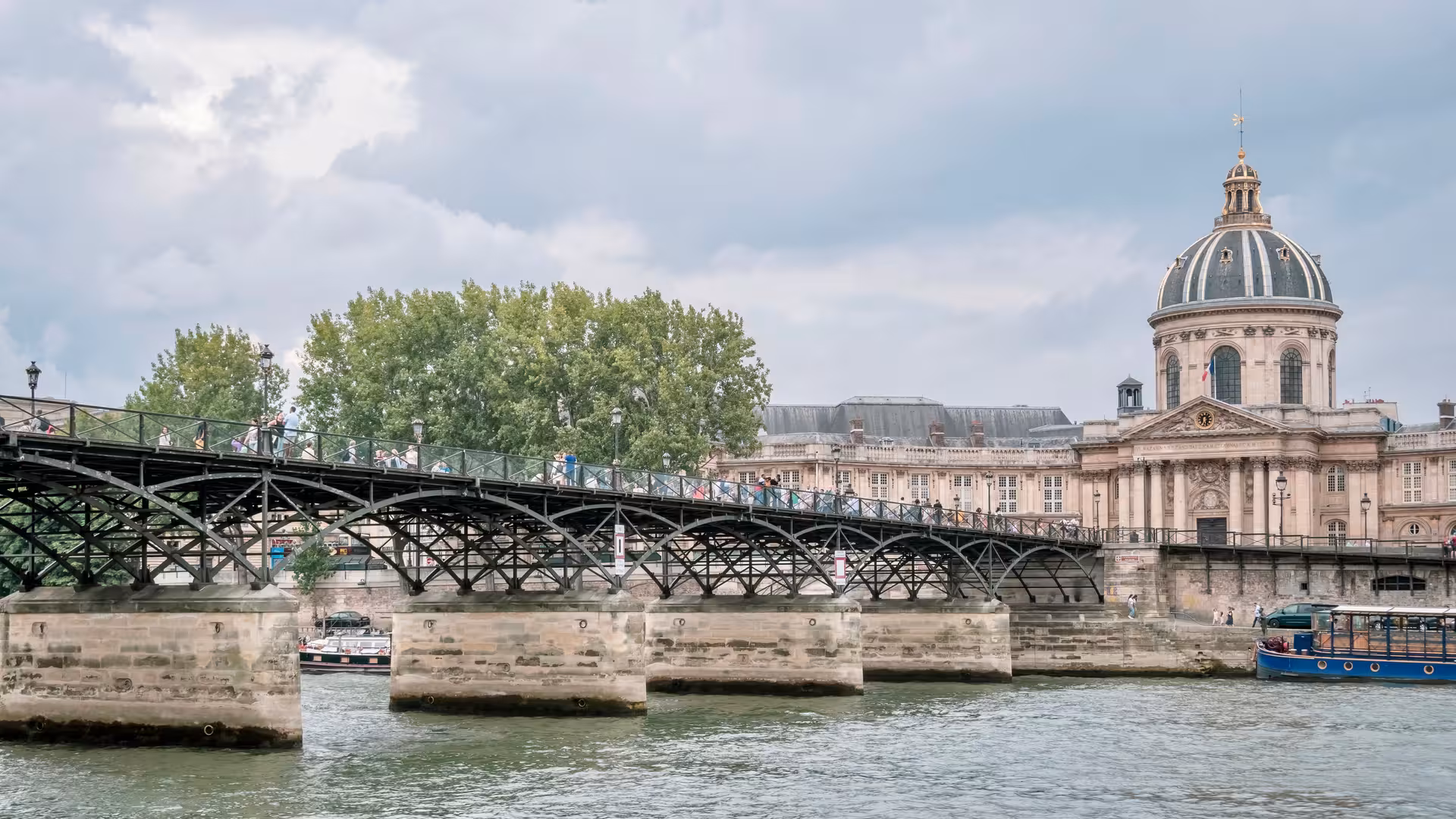 Pont des Arts pedestrian bridge over the Seine River with Institut de France dome in Paris