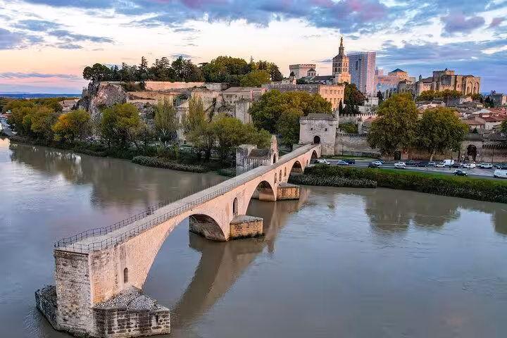 Historic Pont Saint-Bénézet bridge over Rhône River with Avignon Palace at sunset on a Provence private tour.