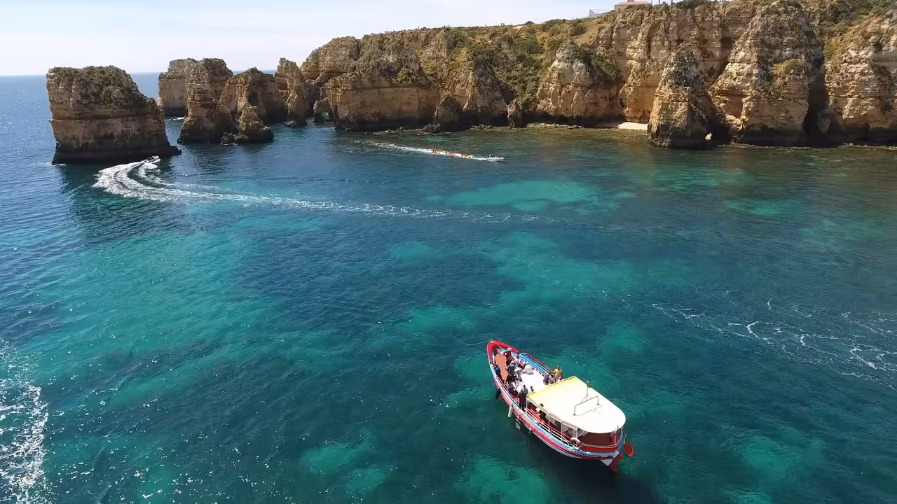 Boat cruising past Ponta da Piedade cliffs and clear lagoons in Lagos, Algarve on a 1h15 coastal tour