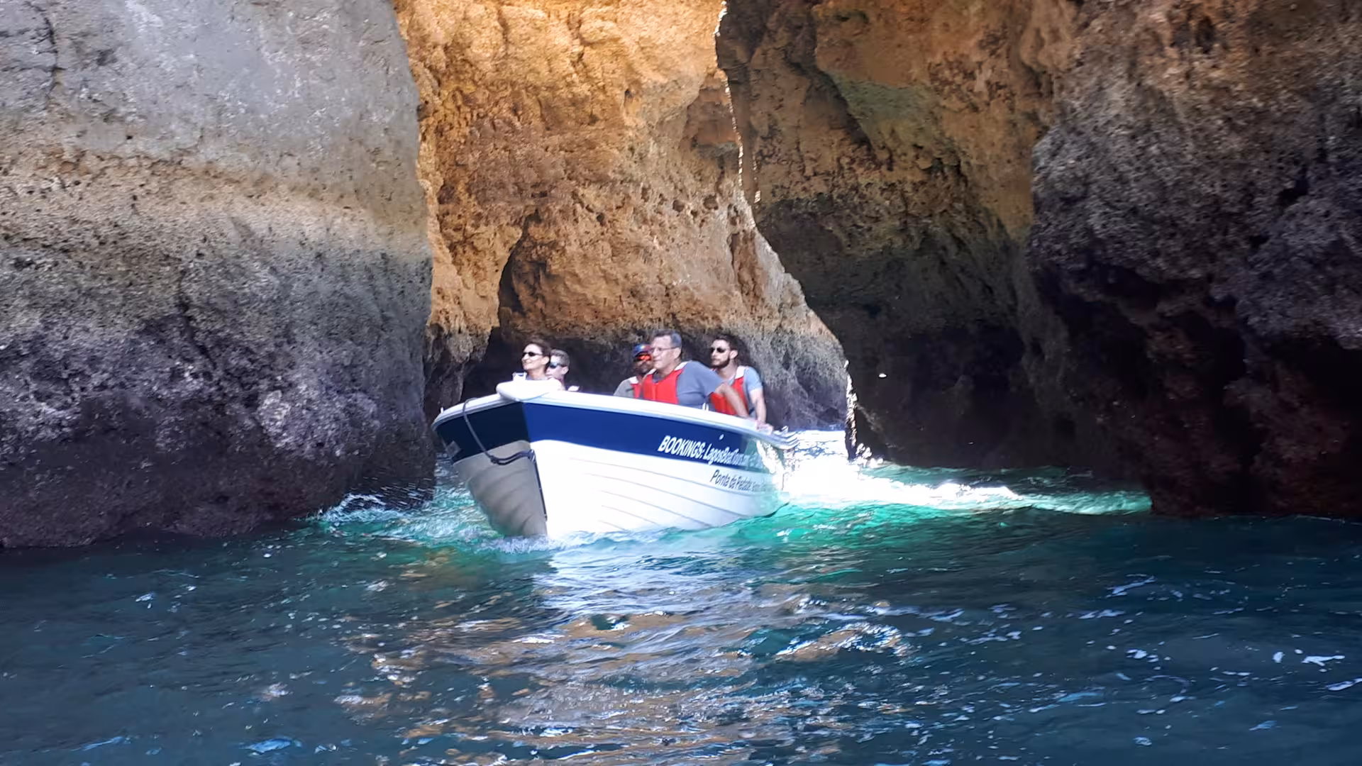 Tourists on a guided boat tour glide through the narrow sea caves and grottoes of Ponta da Piedade near Lagos Algarve