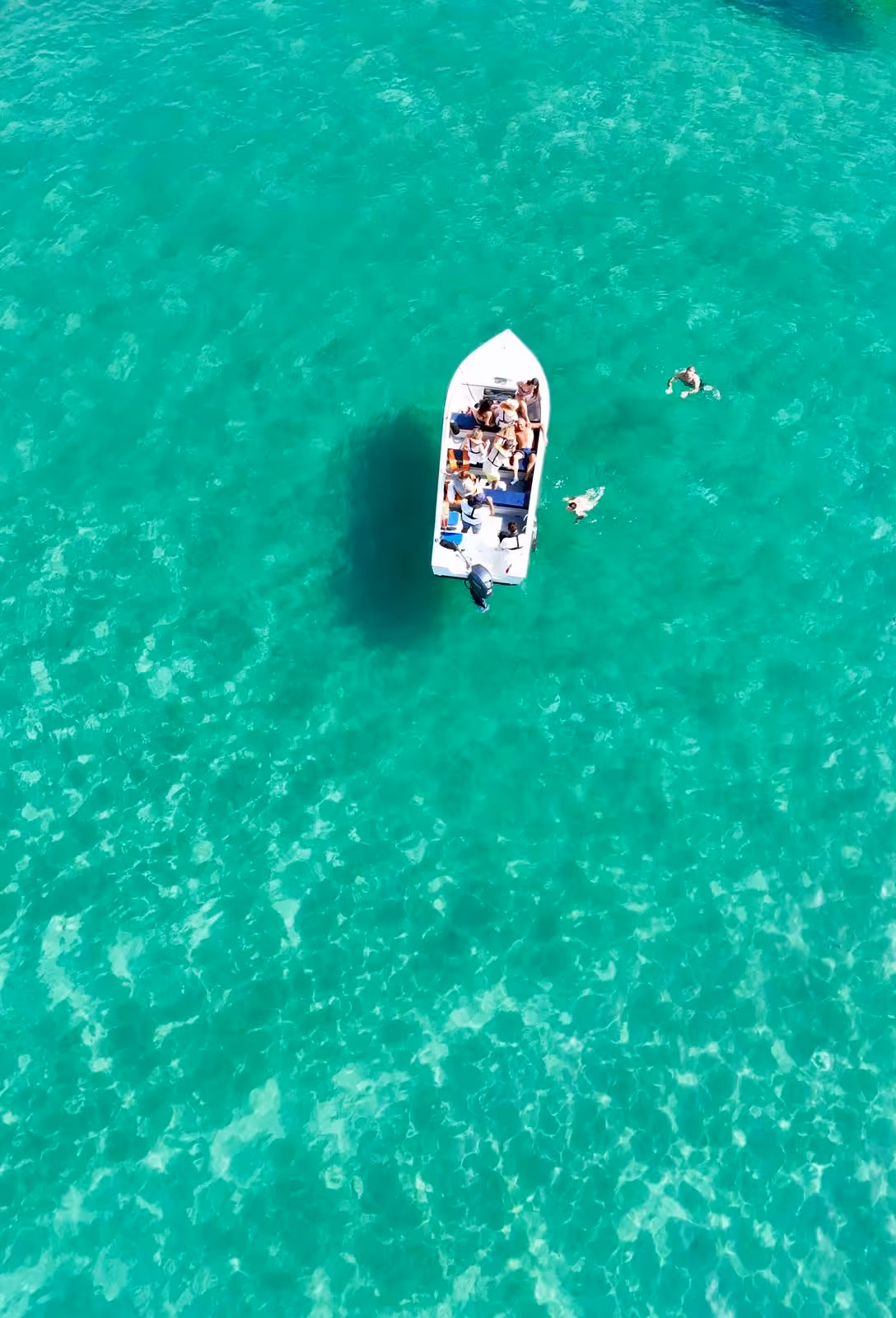 Aerial view of a small boat with guests swimming in turquoise waters on a Ponta da Piedade Lagos sea cave tour