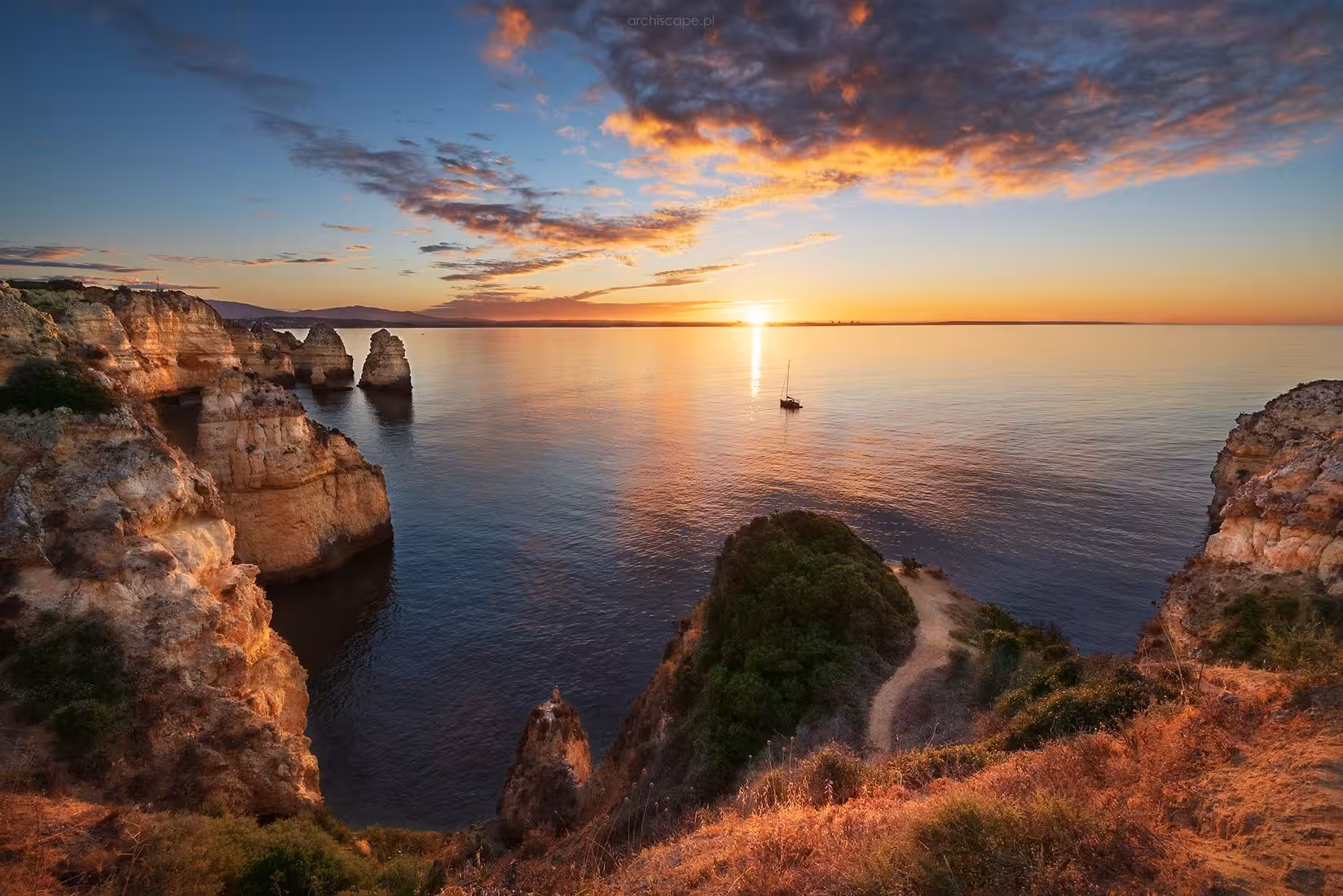 Ponta da Piedade cliffs glowing at sunset near Lagos on a private Algarve cruise with sea stacks and calm water