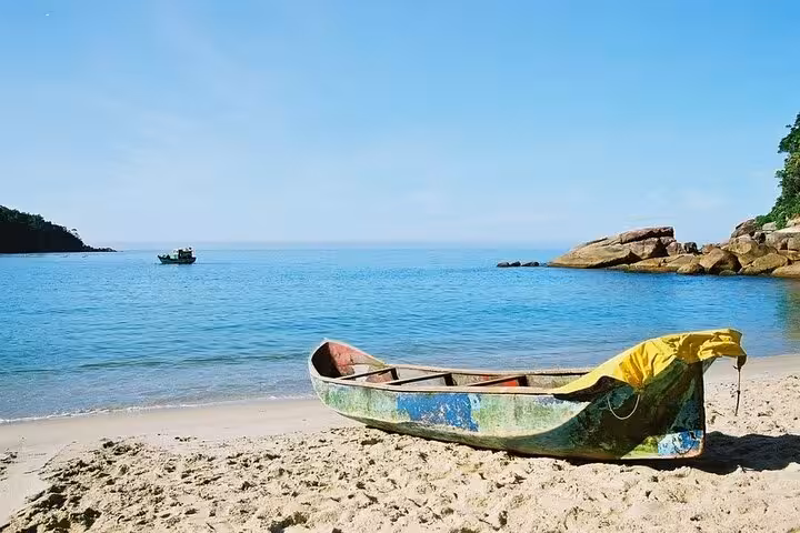 Colorful wooden boat on sandy beach with crystal-clear waters in Ponta Negra, perfect for exploring traditional lifestyles.