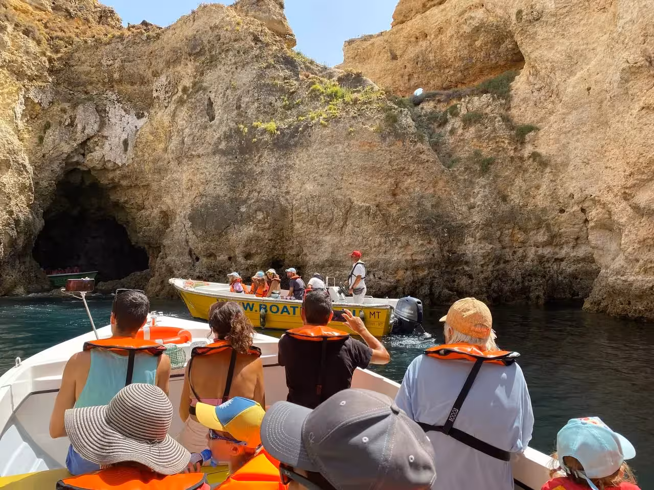 Guests in life jackets approach a limestone cave on Ponta da Piedade express grotto boat tour, Lagos