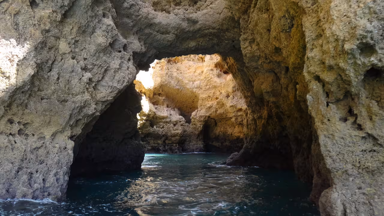 Inside Ponta da Piedade sea cave with sunlit rock arch and calm water on a 2-hour Lagos Algarve boat tour