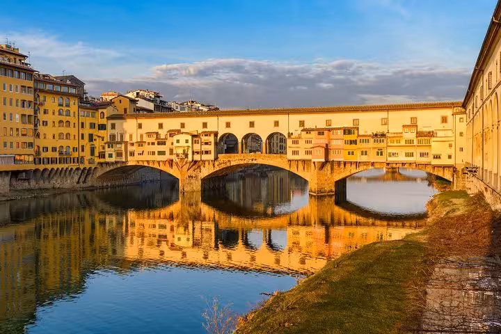 Scenic view of Ponte Vecchio reflecting on the Arno River at sunset during a Florence and Pisa day tour from Livorno.
