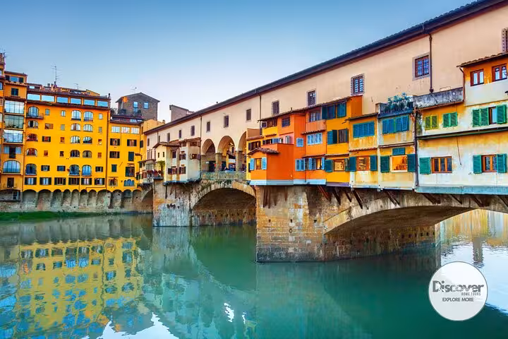 Colorful Ponte Vecchio spanning the Arno River in Florence, Italy, showcasing historic architecture and vibrant reflections.