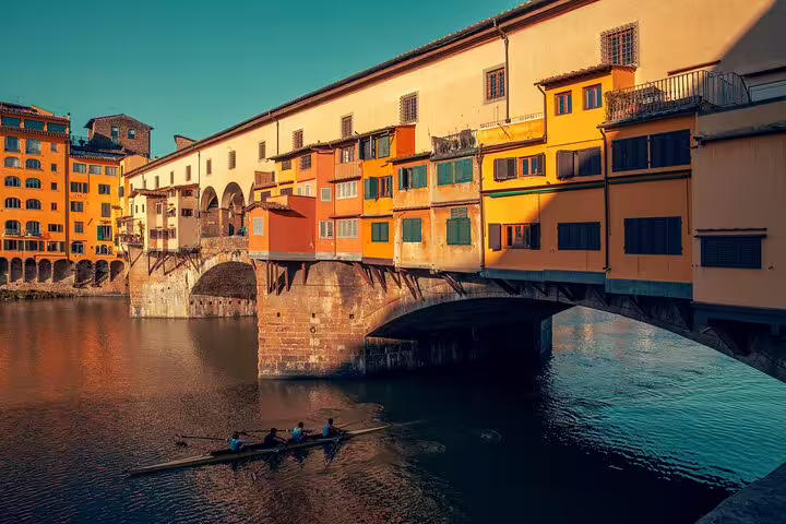 Ponte Vecchio bridge over Arno River with colorful buildings and rowing boat in Florence