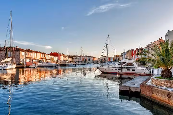 Colorful waterfront buildings and sailboats reflected in the calm canals of Port Grimaud, French Riviera