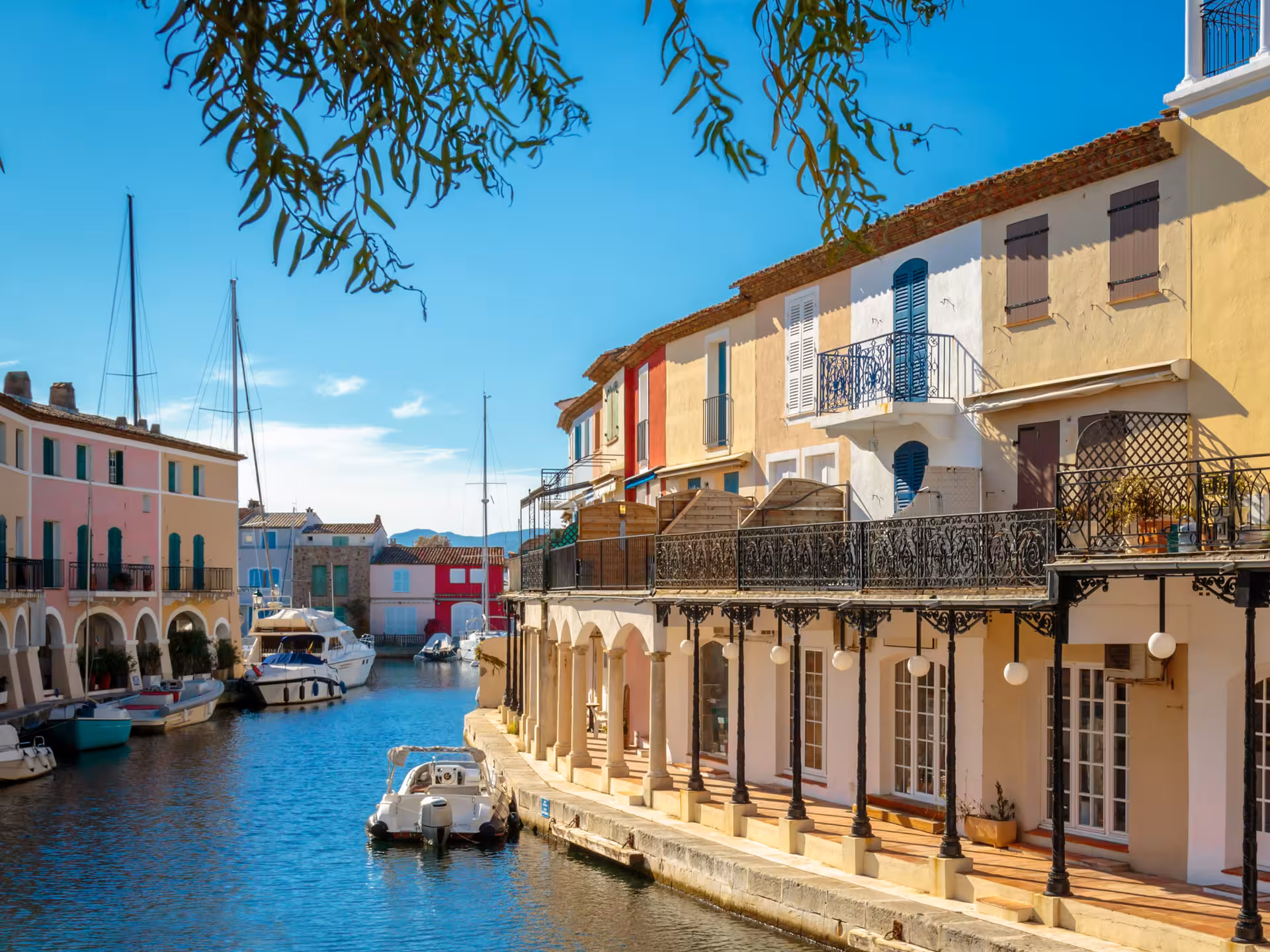 Colorful waterfront buildings and boats along a sunny canal in Port Grimaud, French Riviera