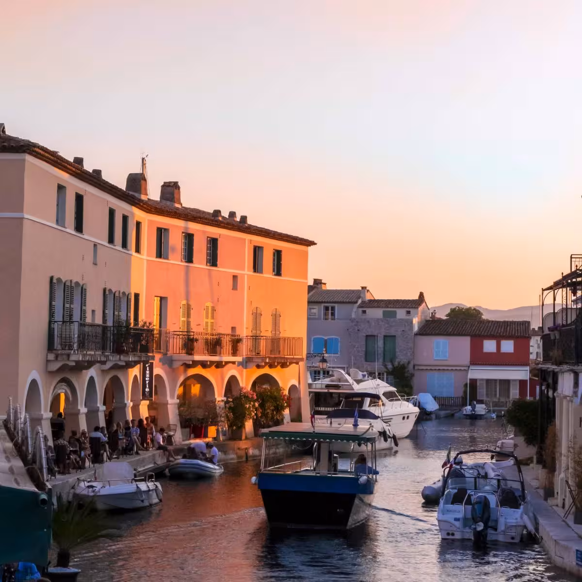 Canal waterway at sunset in Port Grimaud with colorful Mediterranean buildings and moored boats