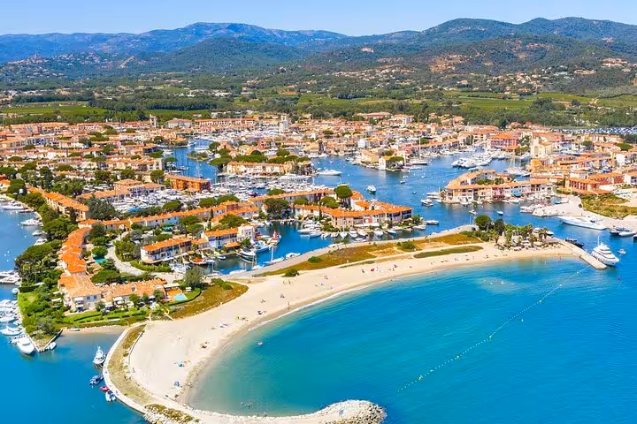 Aerial view of Port Grimaud marina with turquoise water, sandy beach, and colorful waterfront buildings in South France