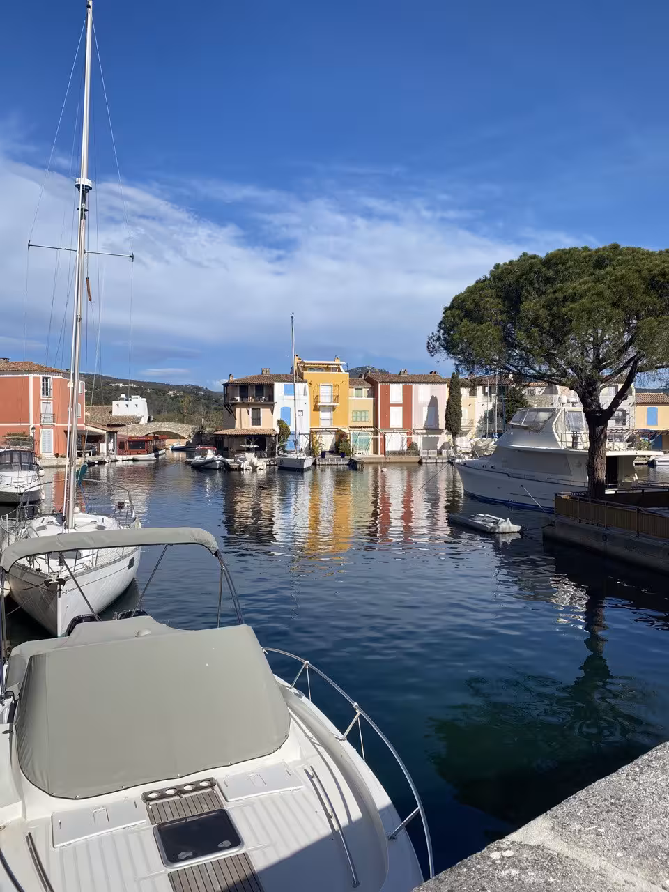 Colorful waterfront buildings reflected in calm canal waters at Port Grimaud marina with moored boats