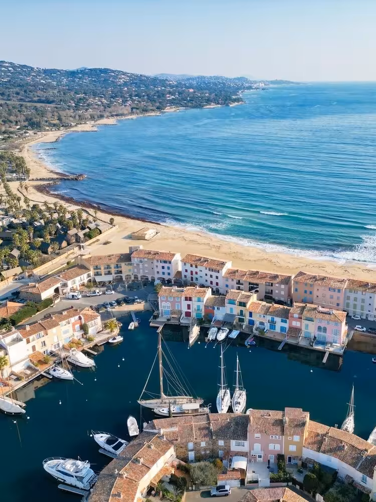 Aerial view of colorful Port Grimaud marina with sailboats and sandy beach near Saint-Tropez, French Riviera