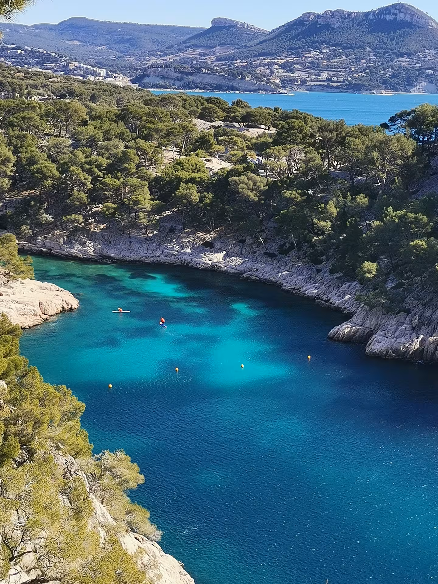Turquoise lagoon at Port-Miou Calanque with kayakers, seen on En-Vau and Port-Pin hiking tour in Calanques Park
