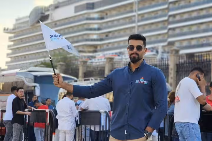 Port Said tour guide holding flag at cruise terminal meeting point for Giza Pyramids tour and Nile lunch