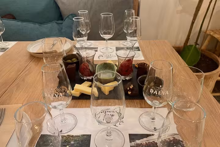 Sommelier-led tasting flight of five Port wines with cheese, olives and chocolate pairings in a cozy Porto venue.