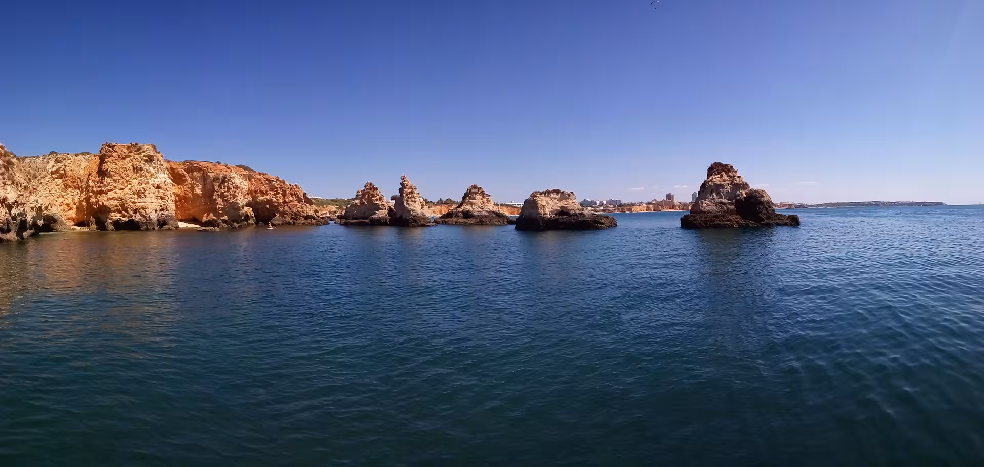 Dramatic sea stacks and golden cliffs off Portimão viewed from the water on a sunny Algarve Seasiren Private Tour 3H
