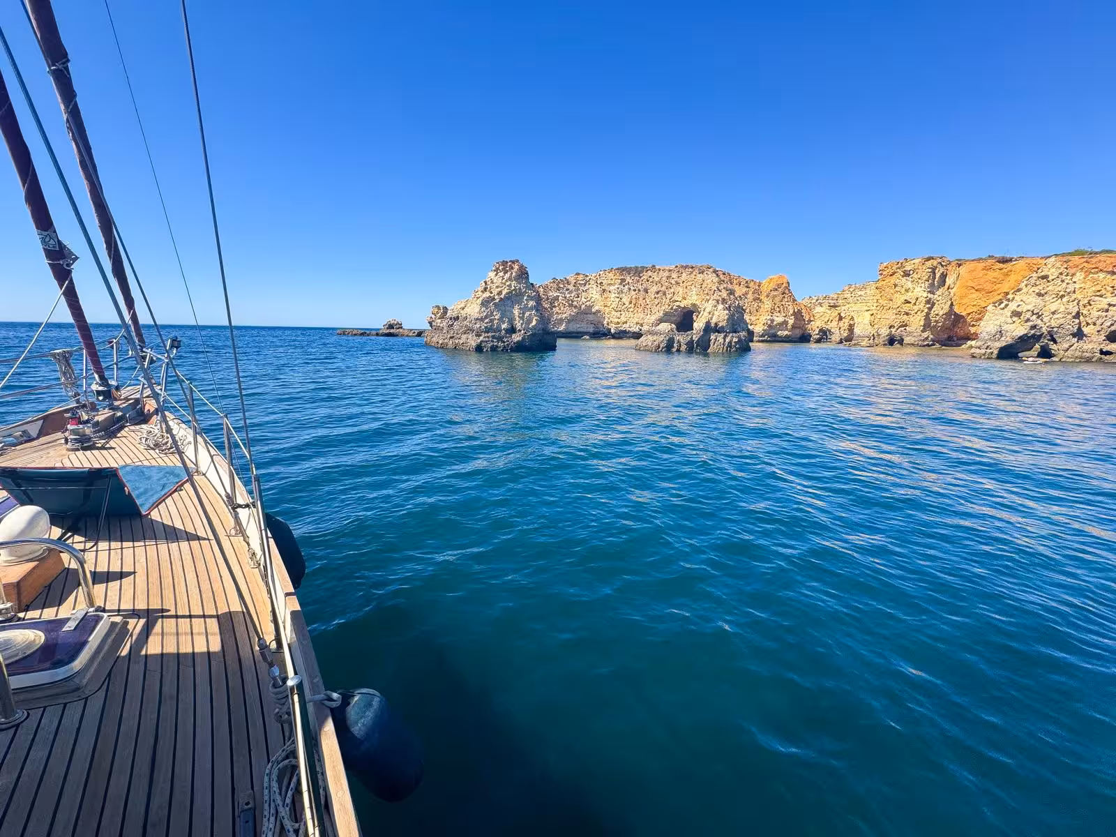 Sailboat deck overlooking stunning Algarve sea caves and golden cliffs on a Portimao sunset sailing tour
