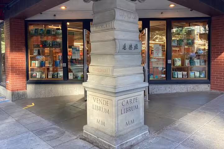 Stone pillar sculpture of stacked books with Latin inscriptions outside a Portland bookstore