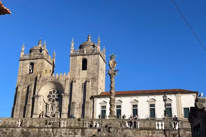 Porto Cathedral Se with ornate medieval stone facade and pillory column under a bright blue sky