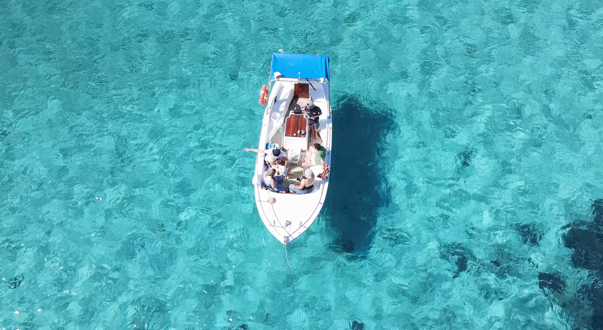 Aerial view of a boat in crystal-clear turquoise waters near Porto Cervo, perfect for a scenic Golfo Aranci tour.