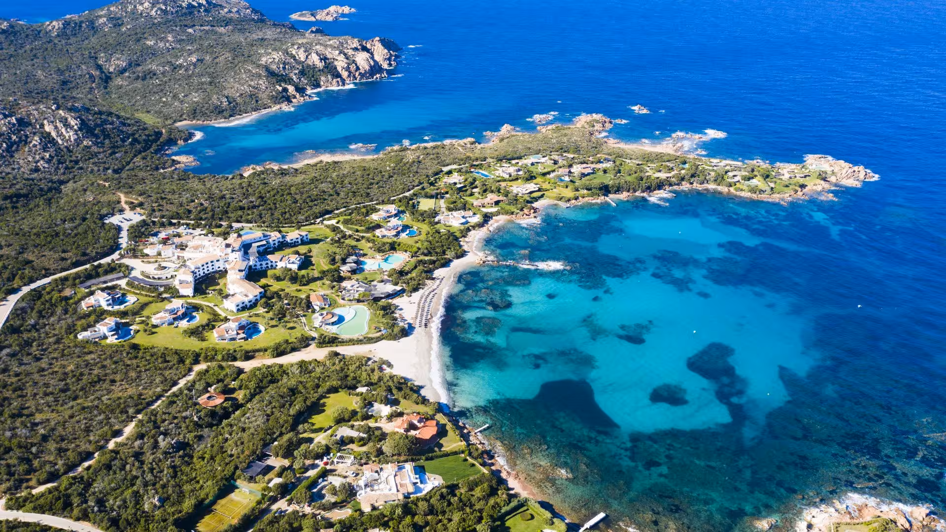 Aerial view of Porto Cervo's stunning coastline with turquoise waters and lush greenery, ideal for dinghy tours.